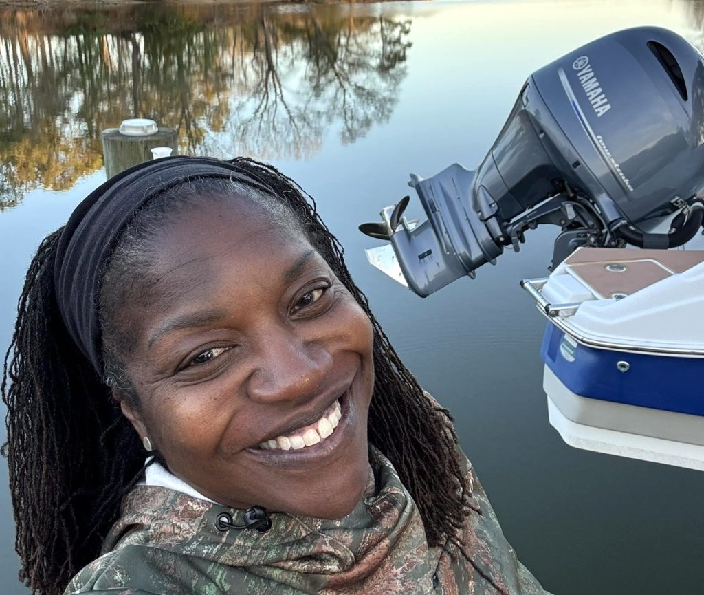 Pat Clemens, the Rivah Sistah, stands in front of her Carolina Skiff boat.