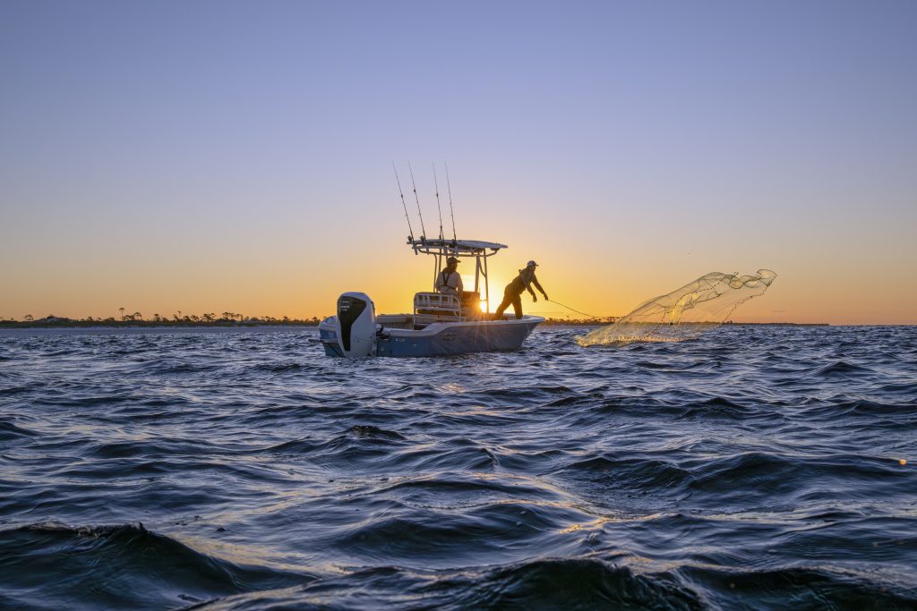Fishermen casting a net offshore on a Carolina Skiff